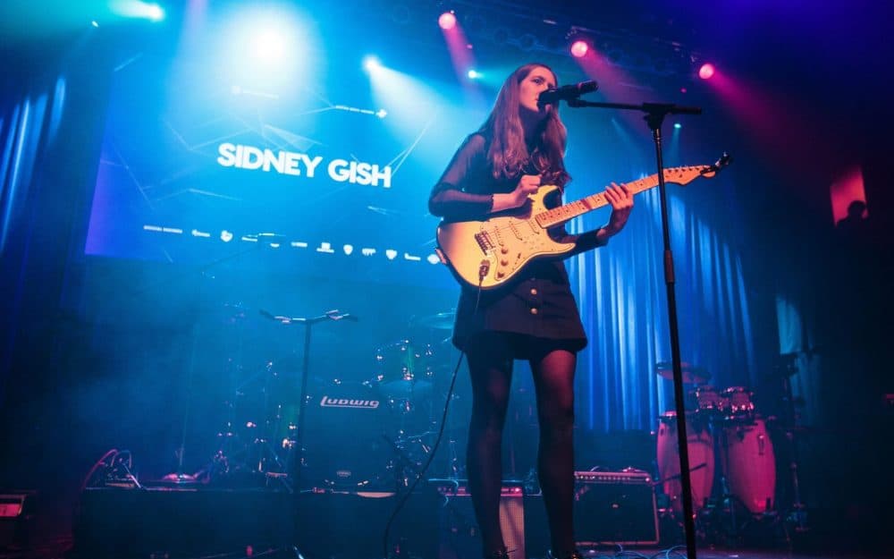 Sidney performing onstage with an electric guitar